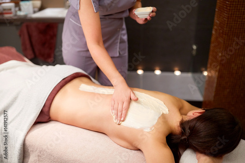 woman having back massage with cream at spa