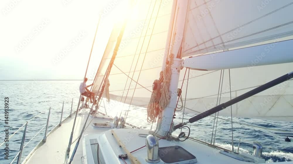 Mann sitzt am bug seiner segelyacht und geniesst die abendsonne