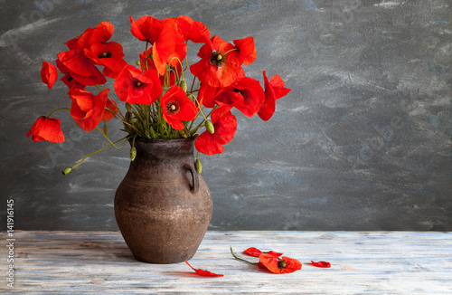 Fototapeta Naklejka Na Ścianę i Meble -  Still life in a rustic style: an old crock and a bouquet of red poppies on a wooden table