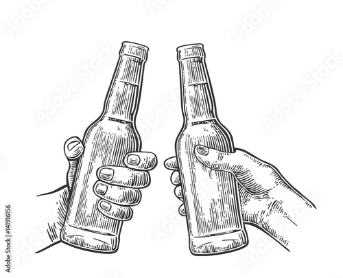 Female and male hands holding and clinking open beer bottles.
