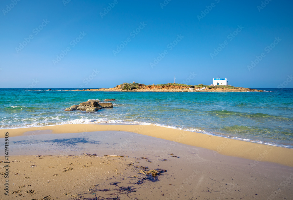 Typical summer image of an amazing pictorial view of a sandy beach with a boat on the beach and an old white church in a small island at the background, Malia, Crete, Greece.