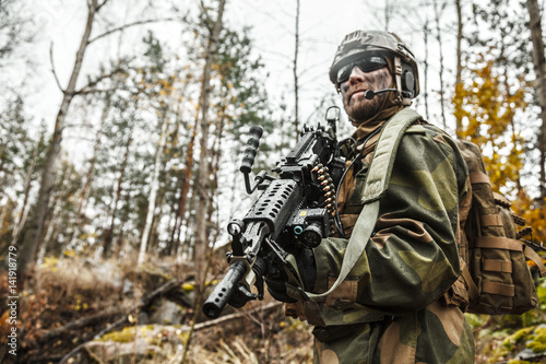 Norwegian Rapid reaction special forces FSK soldier patrolling in the forest. Field camo uniforms, combat helmet and eye-wear goggles are on