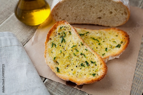 Fried bread with olive oil, garlic and herbs on a wooden table. Rustic style photo