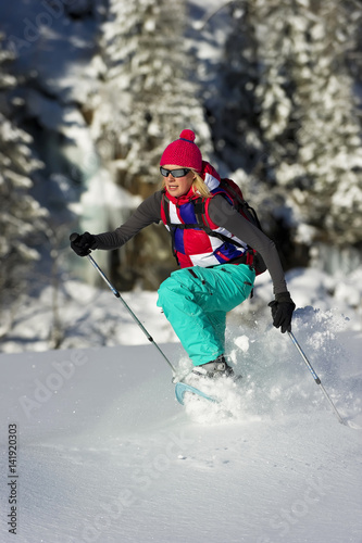 Woman snowshoeing running through deep powder snow.