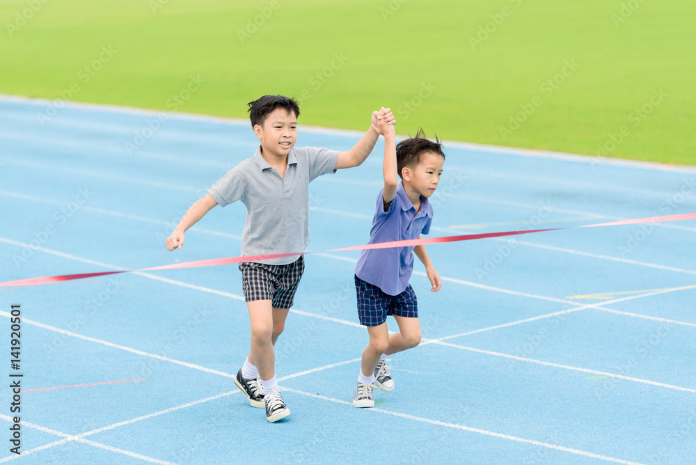 Obraz premium Young Asian boy running on blue track in the stadium