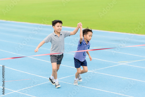 Young Asian boy running on blue track in the stadium © TinPong