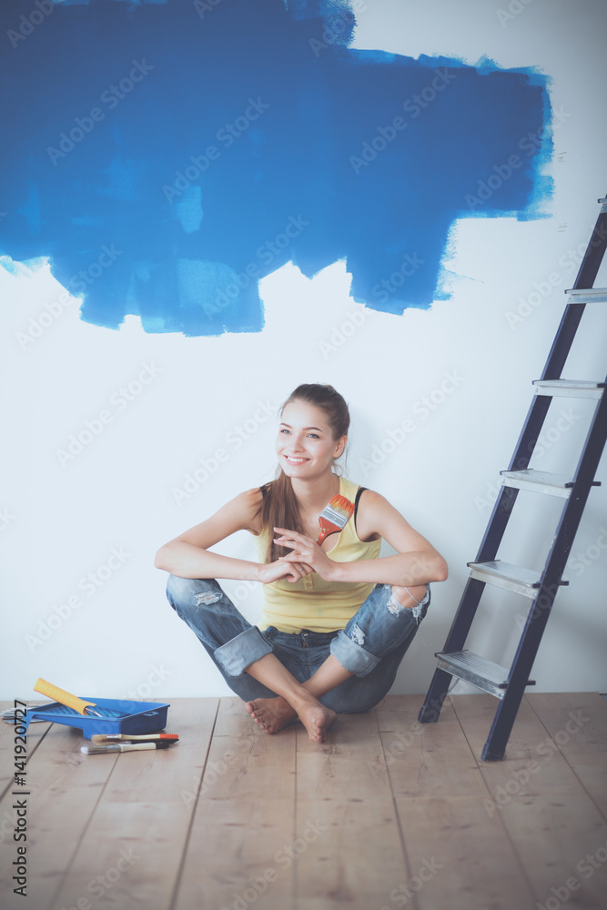 Portrait of female painter sitting on floor near wall after painting