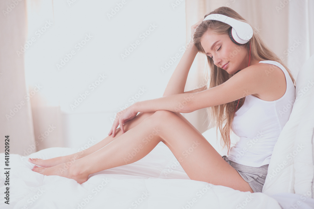 Fototapeta premium Portrait of beautiful woman in morning listening music sitting on bed at home