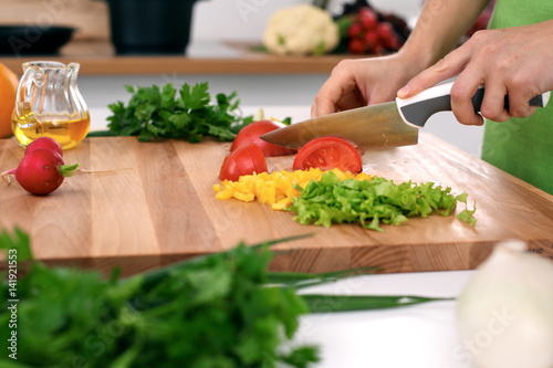 Close up of woman's hands cooking in the kitchen. Housewife slicing ​​fresh salad. Vegetarian and healthily cooking concept