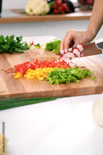 Close up of woman's hands cooking in the kitchen. Housewife slicing ​​fresh salad. Vegetarian and healthily cooking concept