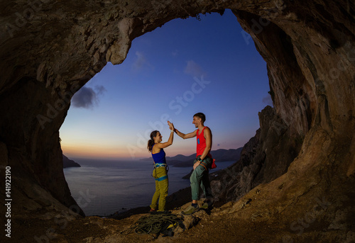 Couple of rock climbers giving high five and cheering