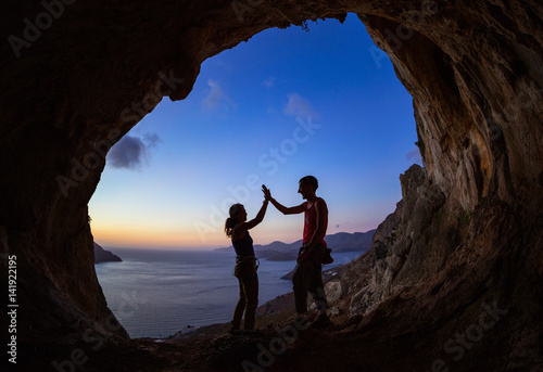 Couple of rock climbers giving high five and cheering