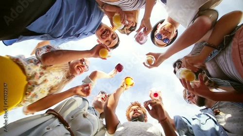 Smiling multi-ethnic friends looking down at camera, toasting and dancing, graded