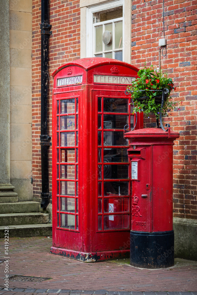 Traditional red post box and the phone booth near a brick wall in Sidmouth, England, United Kingdom Traditional red post box and the phone booth near a brick wall in Sidmouth, England, United Kingdom