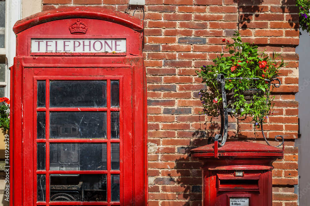 Traditional red post box and the phone booth near a brick wall in Sidmouth, England, United Kingdom Traditional red post box and the phone booth near a brick wall in Sidmouth, England, United Kingdom