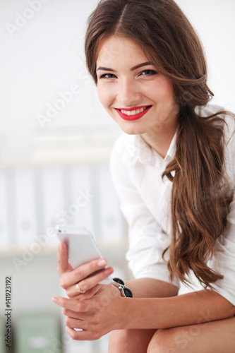 Businesswoman sending message with smartphone in office