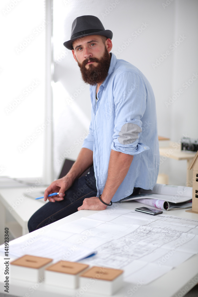 Portrait of male designer in hat with blueprints at desk Portrait of male designer in hat with blueprints at desk