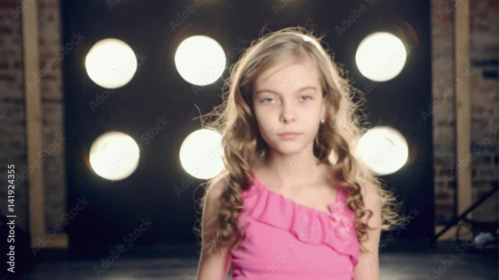 A child model walks the catwalk over in pink dress and posing in front of camera A child model walks the catwalk over in pink dress and posing in front of camera