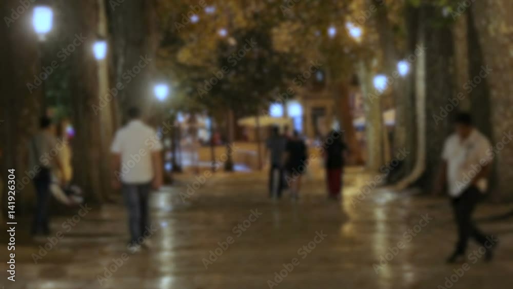 Young people strolling in city park at night, friends hanging out, urban life Young people strolling in city park at night, friends hanging out, urban life