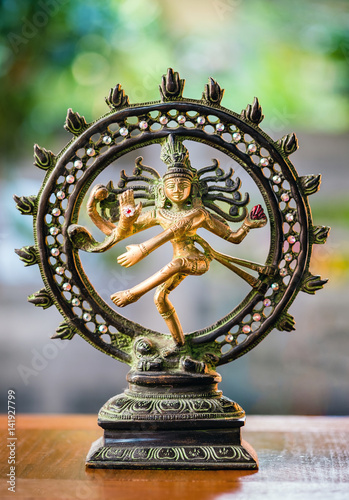 Shiva Nataraja statue on defocus/selective focus background on wooden table. India/Hindu god.