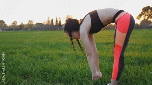 Side view of girl doing standing forward bend outdoors photo