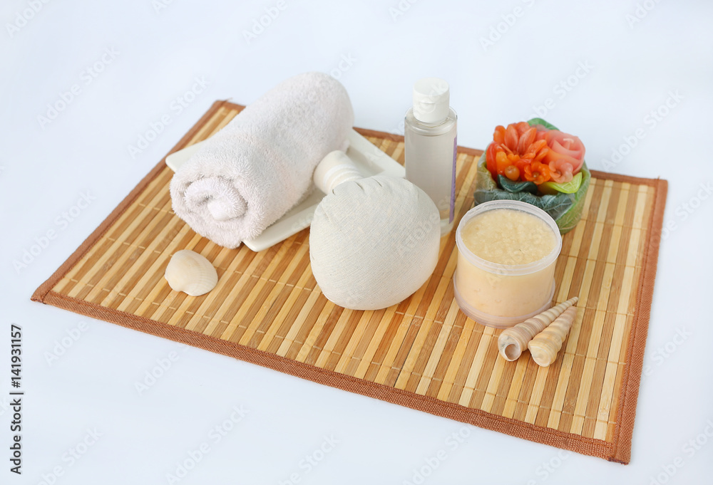 Spa herbal compressing ball with towels and Salt Scrub, Spa concept on bamboo weave mat against white background Spa herbal compressing ball with towels and Salt Scrub, Spa concept on bamboo weave mat against white background