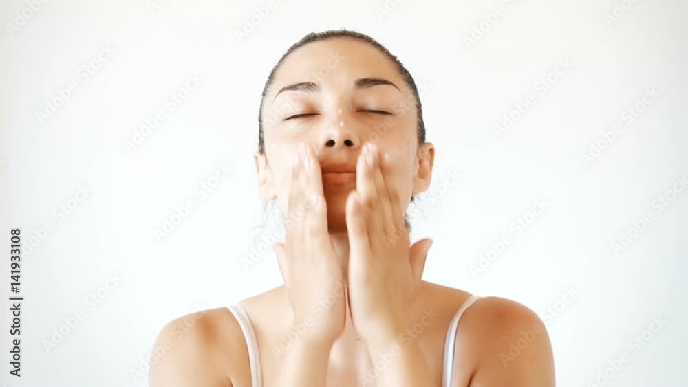 Portrait of beautiful brunette woman applying cream on her face