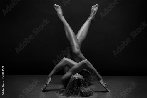Athletic Naked woman body on black background. Fine art photo of female body. 