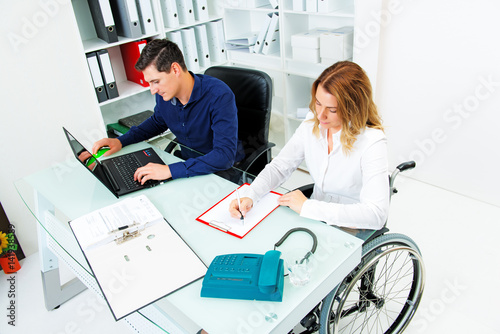 disabled businesswoman in wheelchair and her colleague