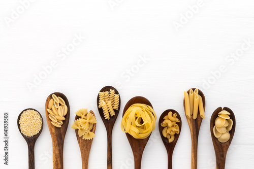 Pasta selection of penne, gnocci, rigatoni, casarecce, fiorelli, pasta Farfalle, pasta A Riso, Orecchiette Pugliesi, Gnocco Sardo and Farfalle in wooden spoons over white background