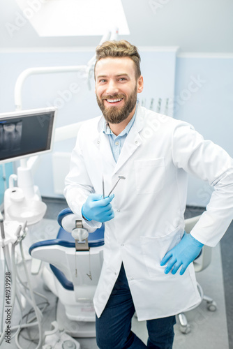 Portrait of handsome dentist in uniform at the dental office