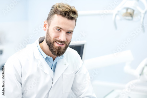 Portrait of handsome dentist in uniform at the dental office