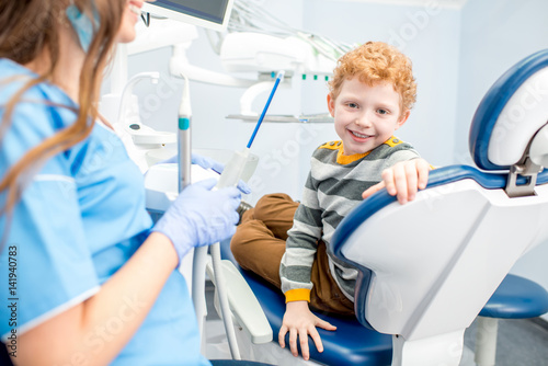 Portrait of a happy young boy with a toothy smile sitting on the dental chair at the dental office