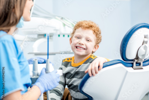 Portrait of a happy young boy with a toothy smile sitting on the dental chair at the dental office