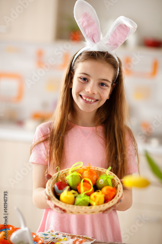 Female child show basket with colorful Easter eggs