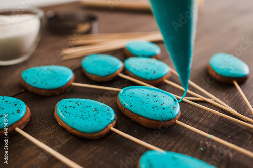 Preparing cookies with blue icing for decoration on rustic wooden table closeup