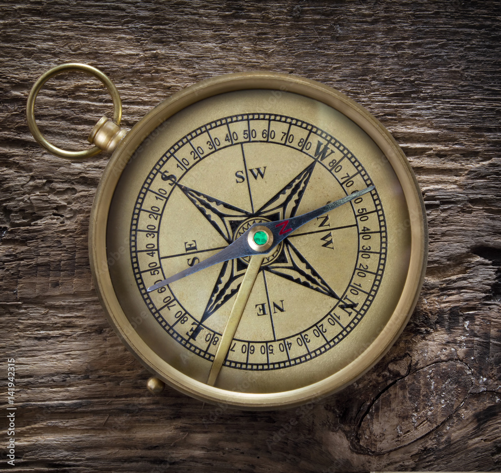 antique compass on grunge wooden background
