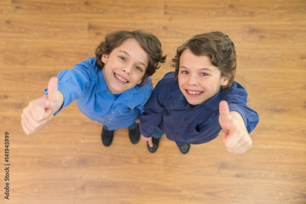 The two curly twin thumb up to the camera. View from above The two curly twin thumb up to the camera. View from above