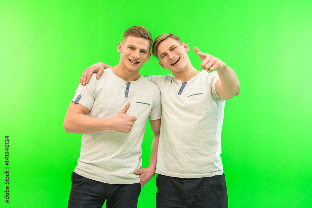 The two happy twin brother gesture on the green background The two happy twin brother gesture on the green background