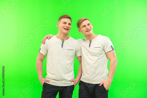 The two happy twin brother stand on the green background