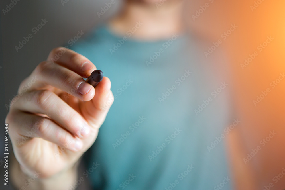 Naklejka premium Hand of man writing on empty glass with a pen