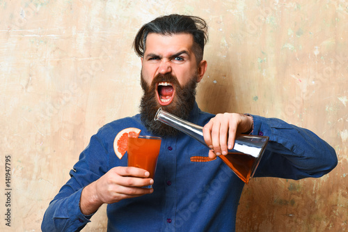 Brutal hipster holding alcoholic shot and glass tube or flask