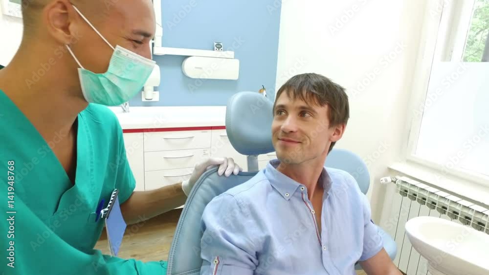 Close up of friendly male dental surgeon with young smiling man Close up of friendly male dental surgeon with young smiling man