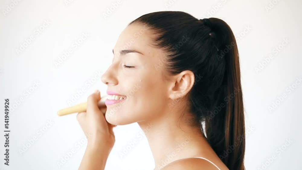 Profile of smiling young woman applying powder on her face Profile of smiling young woman applying powder on her face