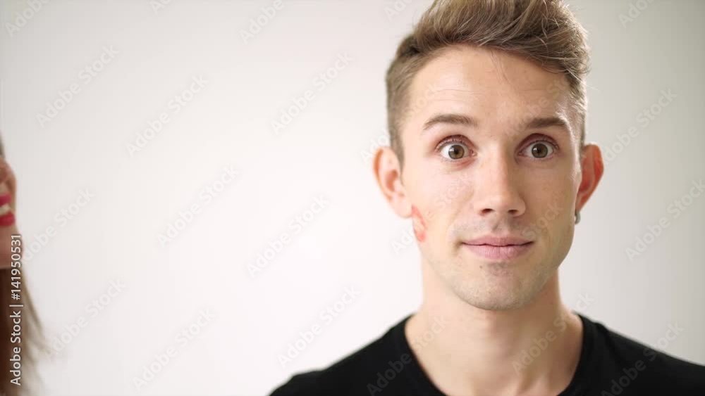 The young man is overjoyed after the kiss girls. On his cheek left a bright red imprint of lips The young man is overjoyed after the kiss girls. On his cheek left a bright red imprint of lips