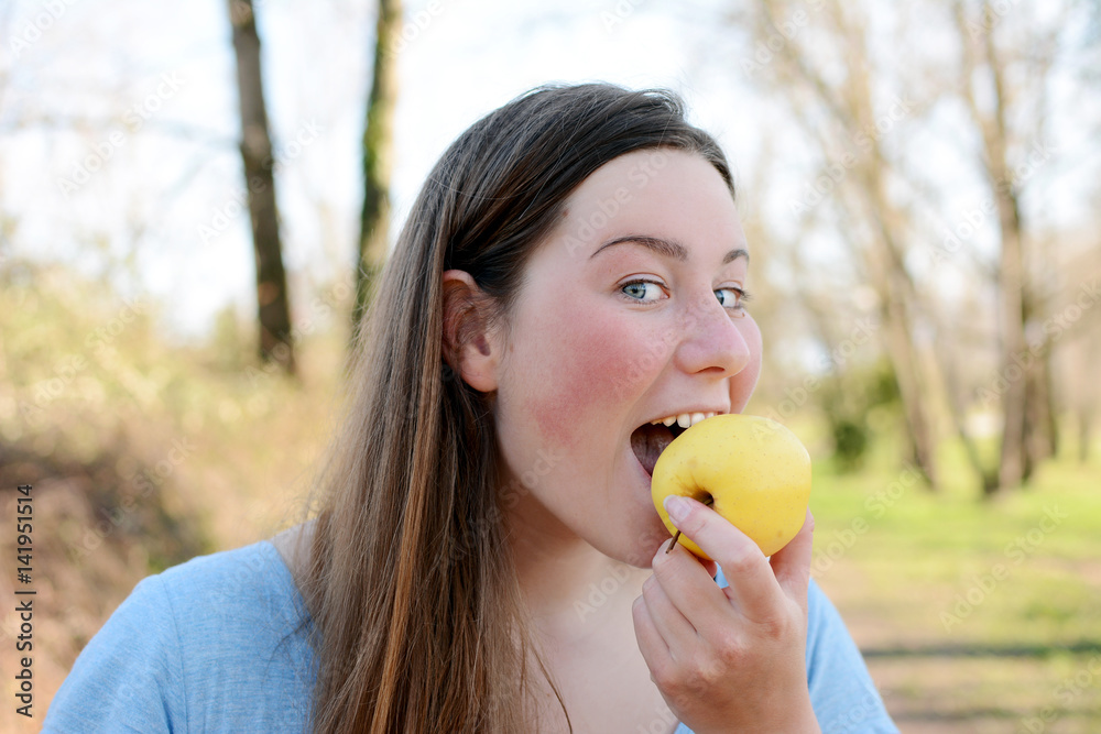 Young happy woman is standing in park and eating apple. Young happy woman is standing in park and eating apple.