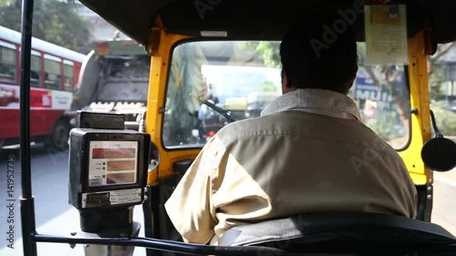 MUMBAI, INDIA - 8 JANUARY 2015: Back view of a local Indian driver of ricksha and charging meter during a ride. 