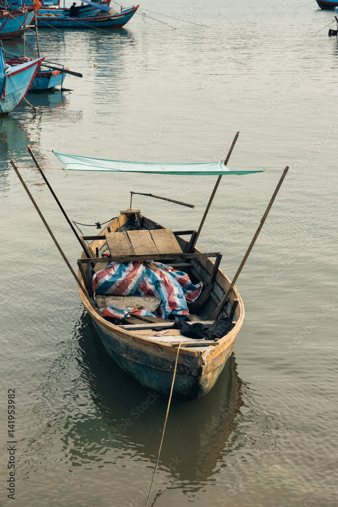 Little lonely fish boat with shed/ Fishing wooden boat at anchor in a sheltered bay on a calm early spring evening