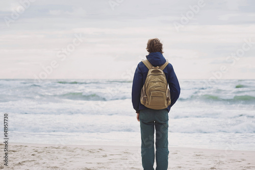 Young man traveler looking at the sea. Travel and active lifestyle concept