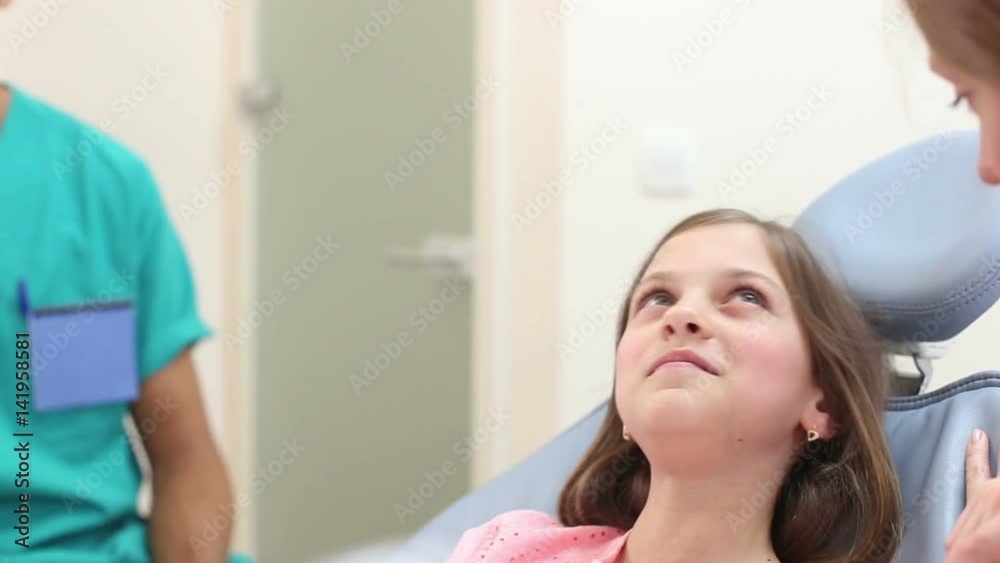 Close up of cute little girl in dental ordination, talking with dentist and assistant Close up of cute little girl in dental ordination, talking with dentist and assistant
